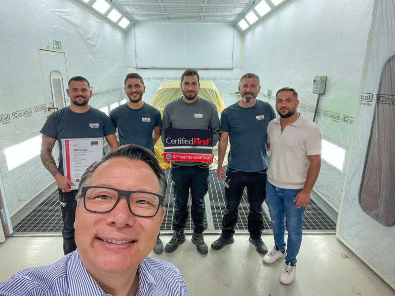 Remise du certificat devant la nouvelle cabine de peinture : le directeur du réseau CFS Richie Schöller (au premier plan) est particulièrement heureux. 