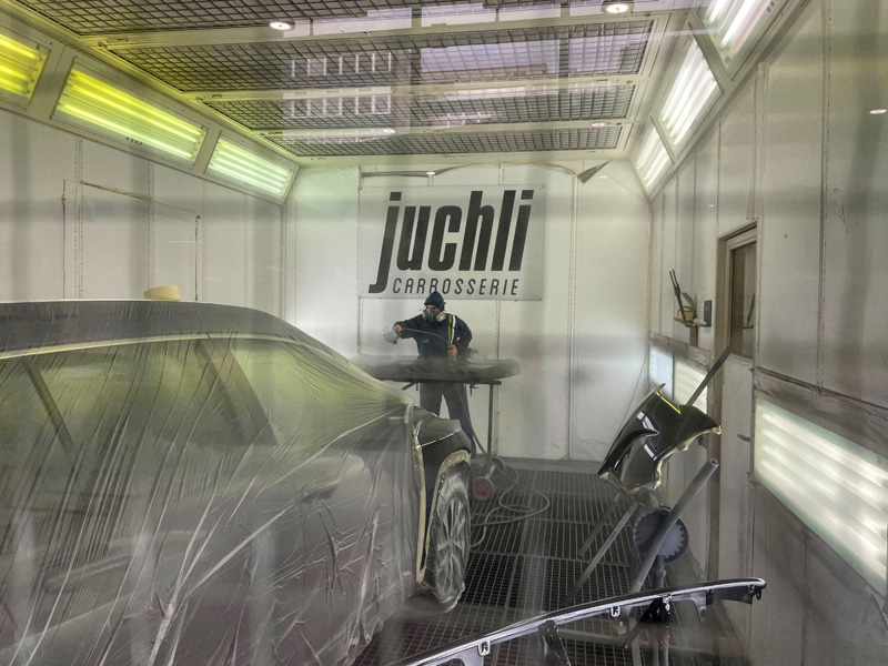 La grande inscription l’indique clairement : nous nous trouvons dans la cabine de peinture de l’entreprise « Juchli AG ».