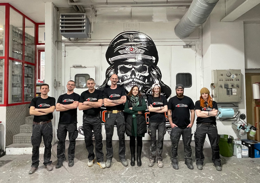 Vor der Lackierkabine mit Firmenmaskottchen: Die «schweren» Jungs und Mädels der Pollinger GmbH. 