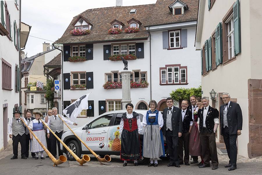 Quand la tradition rencontre la technique : sonneur de cor des Alpes, costumes folkloriques et un S-Cross habillé aux couleurs du festival – ainsi se présente le comité d’organisation du Festival des yodleurs 2026 à Bâle.
