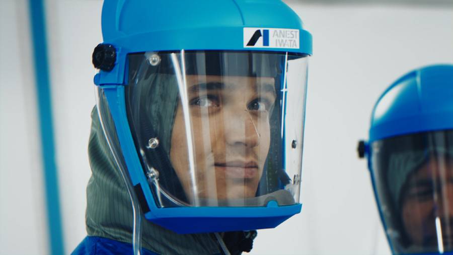 Fokus statt Vollgas: Lando Norris tauscht Helm gegen Visier – bereit für die Sikkens Spray Challenge im McLaren Technology Center.