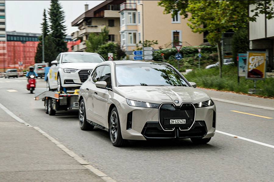 Le BMW iX tire une remorque lourdement chargée à travers la ville comme s’il s’agissait d’une formalité. Une scène qui illustre la sérénité des SUV électriques sous charge – même si leur appétit énergétique grimpe rapidement en arrière-plan.
