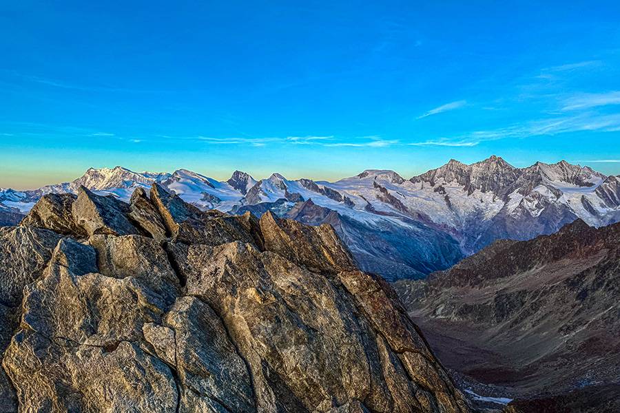 Sur l’arête entre quotidien et adrénaline : roche rugueuse au premier plan, amphithéâtre de 4000 valaisans au fond. Là-haut, Bühlmann commence à raconter – et les montagnes écoutent.