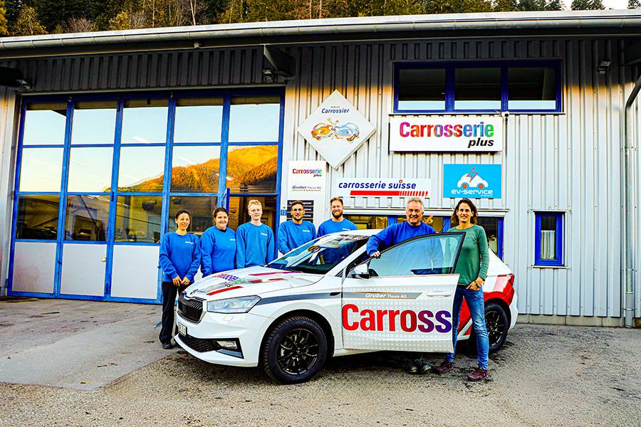 Rico Gruber (à la portière) avec son épouse Kim et l’équipe devant son entreprise à Thusis…