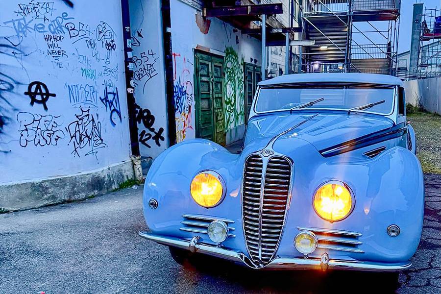 Crépuscule, phares jaunes, ligne nette : le Delahaye 135 MS dans sa version la plus photogénique — aristocratique, présent, et peut-être plus beau qu’au jour de sa livraison.
