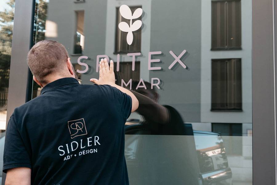 Christian Sidler bei der Montage einer Fensterbeschriftung: Präzisionsarbeit von Hand – damit Gestaltung nicht nur gut aussieht, sondern auch dauerhaft hält.