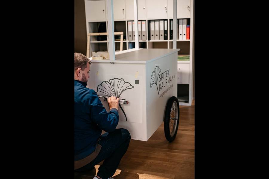 Beschriftung eines Holzwagens: Feinarbeit auf ungewohntem Untergrund – auch mobile Sonderlösungen erhalten bei «Sidler Art + Design» ein klares, stimmiges Erscheinungsbild.