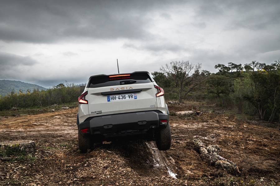 Vue arrière du Dacia Duster sur le parcours tout-terrain – des éléments robustes en plastique et la signature lumineuse distinctive soulignent le caractère fonctionnel de ce classique.
