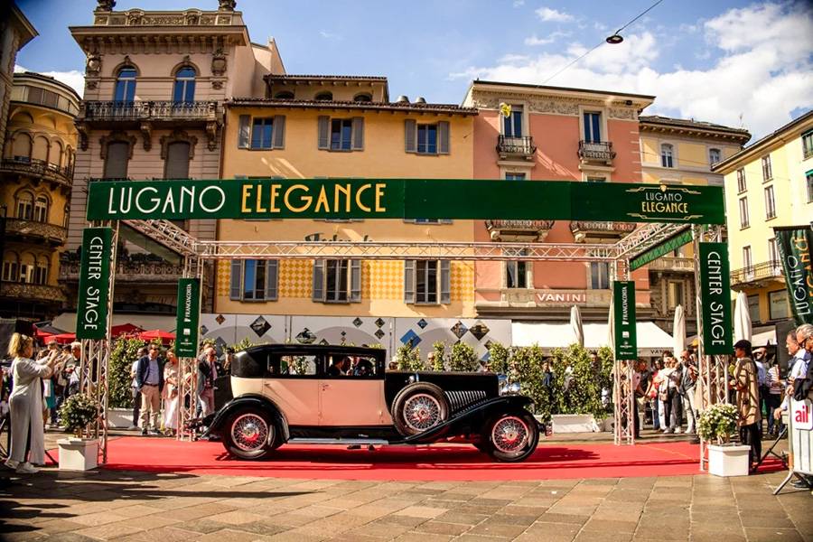 Auf der Piazza Riforma wird Lugano zur offenen Bühne für rollende Eleganz: Ein Vorkriegsklassiker passiert den Center Stage des Lugano Elegance vor historischer Stadtkulisse.