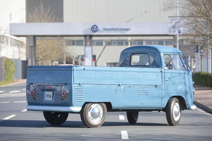 Le Bulli pick-up de 1956 devant l’usine de Hanovre: 30 ch, un plateau ouvert et une solide éthique du travail – un Transporter des débuts, issu de la première année de production du site.