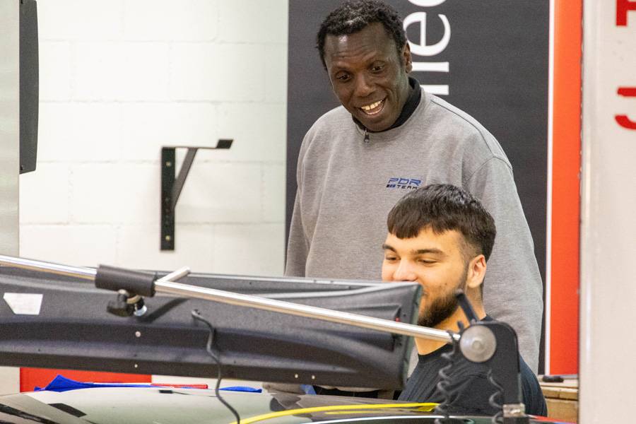 Moussa Diallo beobachtet die Arbeit am Bauteil und gibt praktische Hinweise. Beim Dellendrücken zählt nicht Kraft, sondern der richtige Blick für Spannung, Tiefe und Formverlauf.
