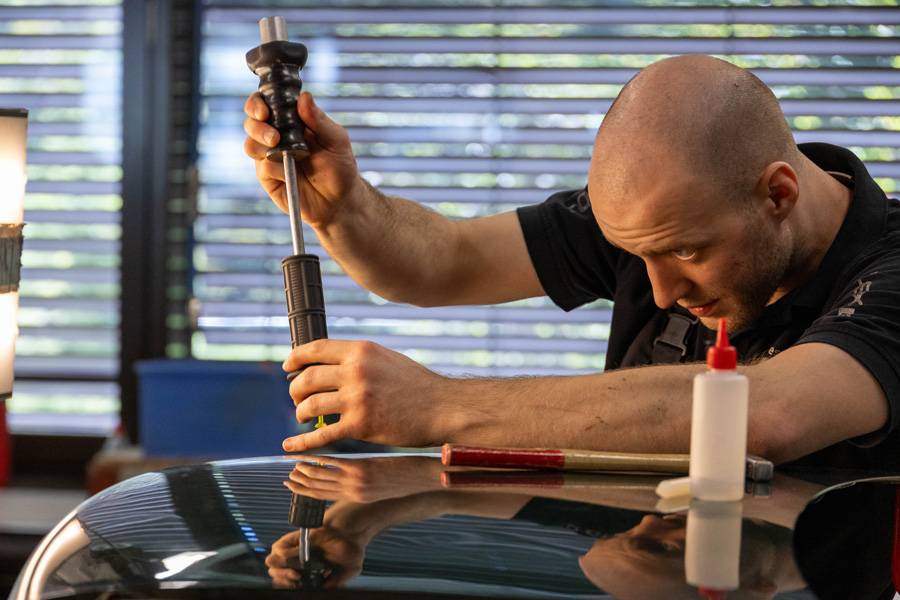 Daniel Furac von Wüest Carrosserie Amriswil beim Dellenziehen. Hier braucht es dosierte Kraft und viel Gefühl – ein zu harter Zug kann aus der Delle schnell eine Erhebung machen.