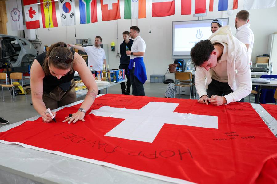 Gute Wünsche mit Filzstift: Die Mitglieder des Champions-Clubs unterschreiben die Schweizer Fahne, die Gilles Glauser und Davide Manieri auf ihrem Weg an die World Skills 2026 nach China begleiten wird.