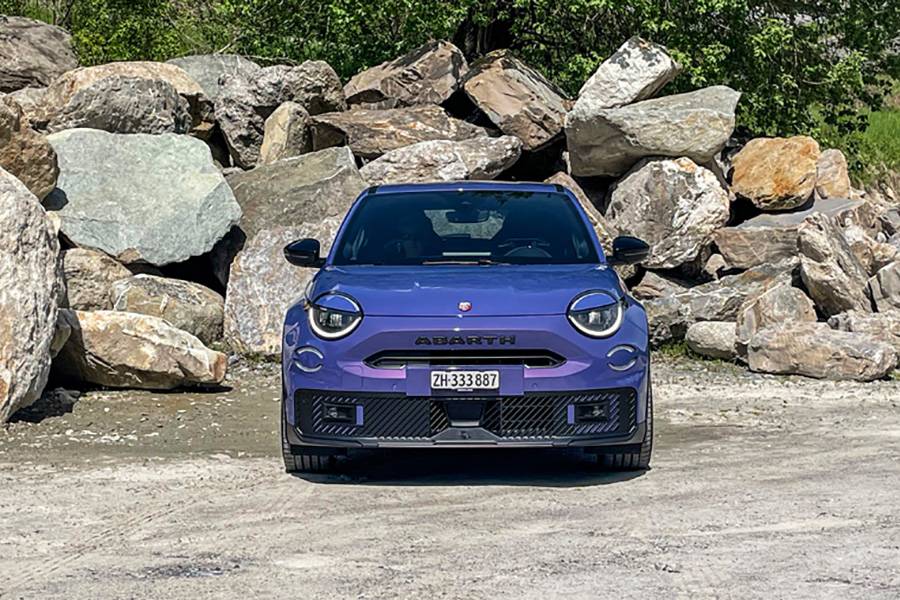 Large, basse, violette: vue de face, l’électrique annonce d’emblée qu’elle n’a rien d’un sage crossover à batteries. La proue, avec son grand lettrage, son imposante prise d’air inférieure et sa lèvre noire, donne le ton.