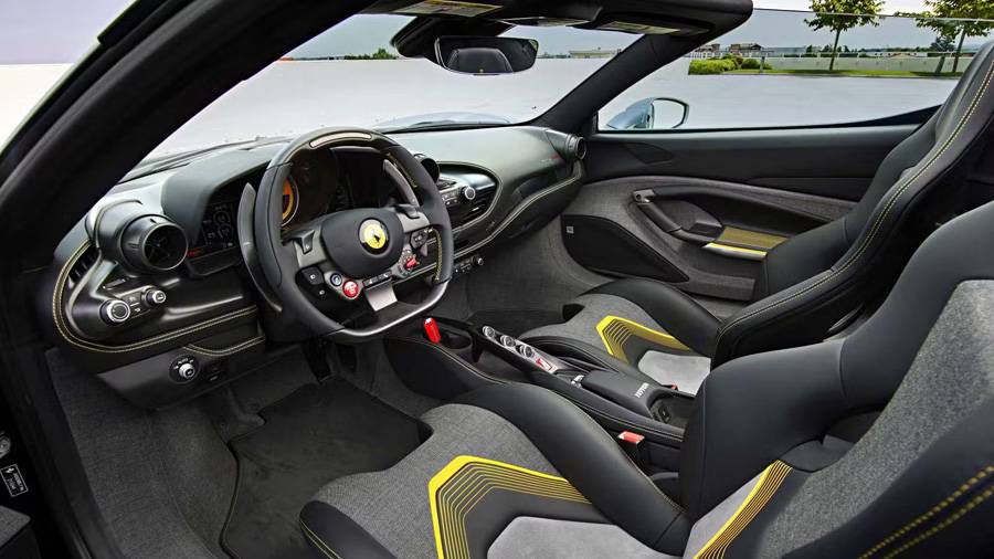 À bord, les origines restent visibles, mais l’exécution impose sa propre signature: surpiqûres jaunes, motifs spécifiques des sièges et cockpit entre technique de course et costume sur mesure.