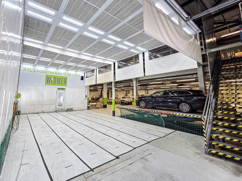 Die XXL-Kabine (17,30 x 7,30 m) für Lastwagen, Kommunal- und Baumaschinen. Mit dem Fahrzeuglift gelangt man in den oberen Stock (600m2), wo die Aluca-Innenausbauwerkstatt, ein Spot-Repair- und sechs Abstellplätze sowie sieben Finish- und Aufbereitungsflächen warten.