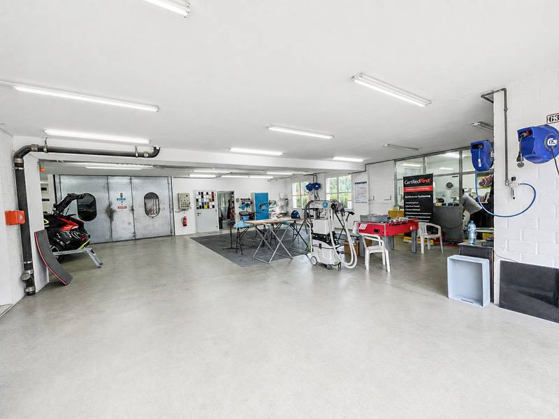 Blick in die Werkstatt: Links die Lackierkabine, rechts das Büro mit direkter Sicht ins Geschehen – kurze Wege, klare Abläufe und ein Arbeitsplatz, bei dem man sieht, dass hier nicht nur geredet, sondern gemacht wird.