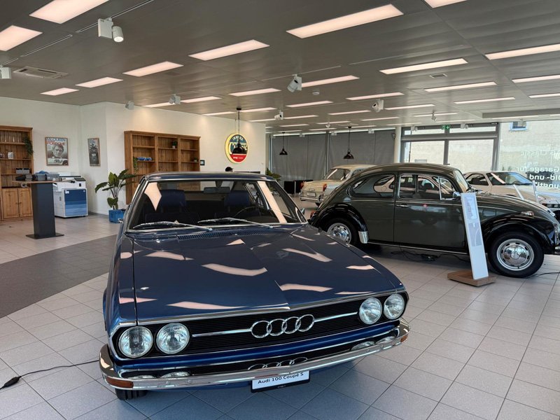 Mit vier Rundscheinwerfern zeigt der Audi 100 Coupé S sein markantes Gesicht. Daneben steht der Käfer für die vertrauten Formen des damaligen Alltags.