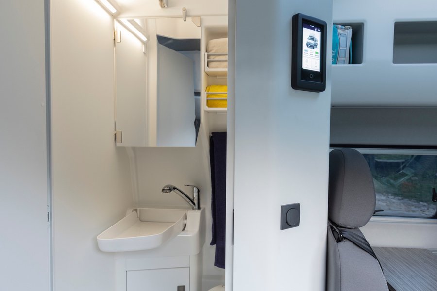 Das eigene Bad fährt mit: Die kompakte Nasszelle bietet unter anderem ein klappbares Waschbecken. Direkt daneben sitzt die Bedieneinheit für die Campingfunktionen. Foto: Volkswagen Nutzfahrzeuge (Werkfoto Hannover).