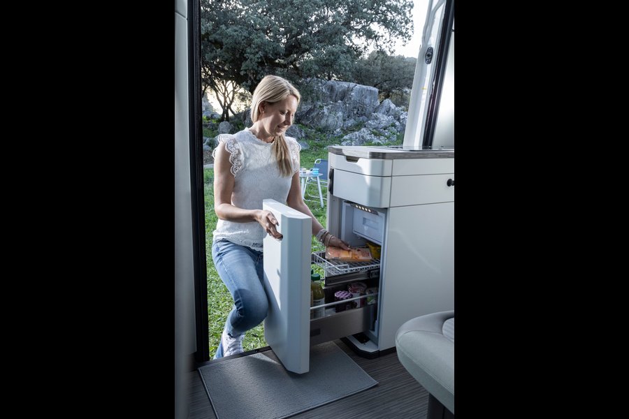 Pour attraper une boisson fraîche, nul besoin de monter à bord : le tiroir du réfrigérateur est également accessible depuis l’extérieur, porte coulissante ouverte. Photo : Volkswagen Nutzfahrzeuge (photo d’usine, Hanovre).