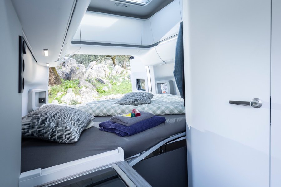Le lit est déjà prêt. Installé à demeure à l’arrière, il fait partie des atouts du Grand California et permet de laisser le coin repas en place le soir. Photo : Volkswagen Nutzfahrzeuge (photo d’usine, Hanovre).