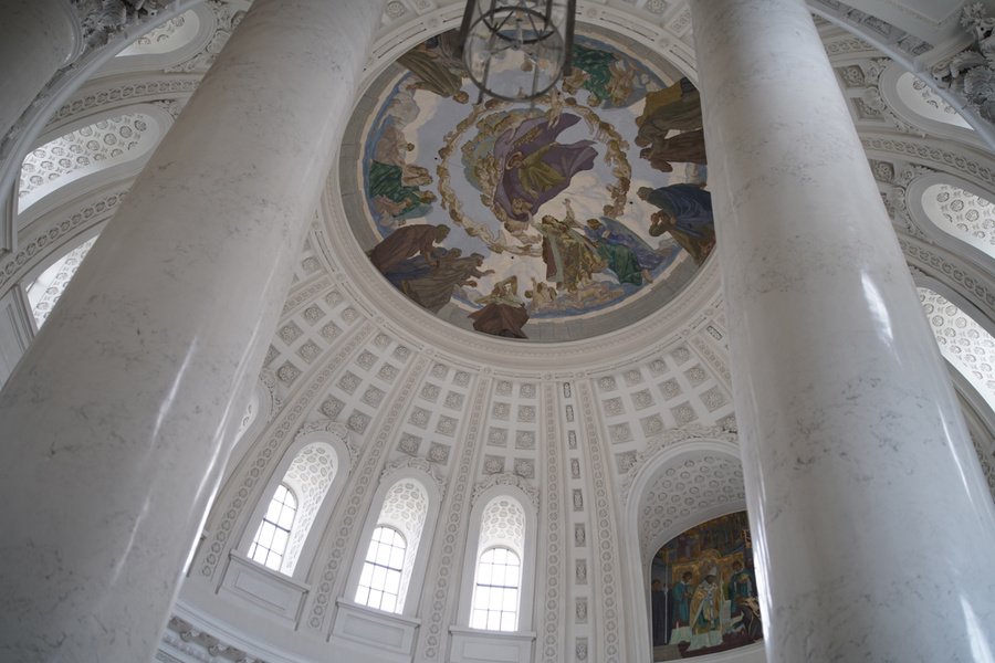 En levant les yeux, on découvre la peinture colorée du plafond, qui se détache entre les colonnes claires et les surfaces de stuc de l’abbatiale. Photo : Jürg A. Stettler.